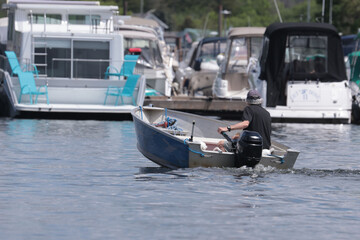 Fisherman bringing small aluminum boat into dock with bigger boats in background
