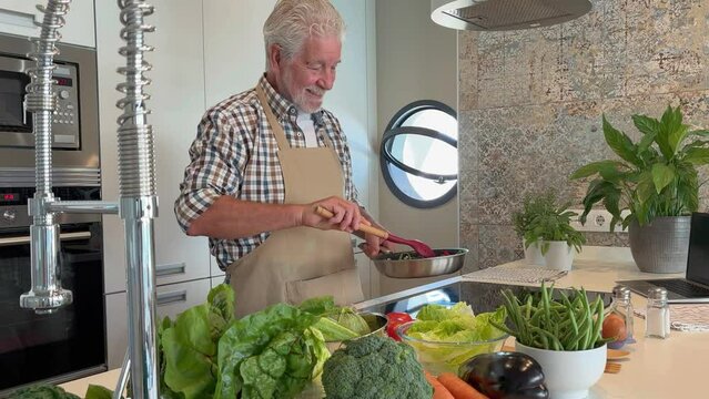 Man at home cooking vegetable in a pot with a table spoon. People in the kitchen preparing dinner. One mature male alone cooking. Real lifestyle person testing taste and cook preparation