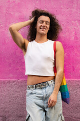 Portrait of gay man with sensual pose smiling at camera isolated on pink background