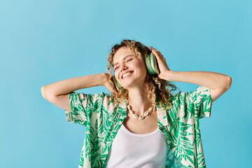 Woman in headphones listening to music against blue backdrop.