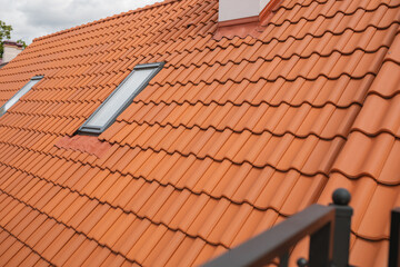 The mansard roof with windows covered with red tiles.