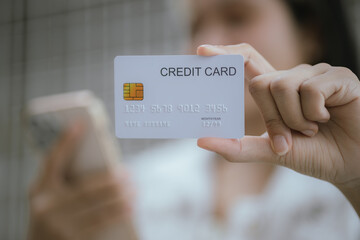 Attractive millennia Asian female holding her smartphone and credit card, using mobile banking app...