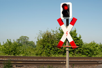 Andreaskreuz vor einer Bahnübergang mit roter Ampel
