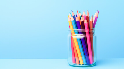 Fototapeta premium a jar of colorful sharpened pencils against a light blue background, highlighting a variety of hues