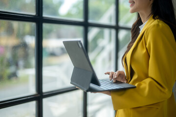 A woman in a yellow jacket is holding a laptop