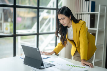 A woman in a yellow jacket is looking at a computer screen