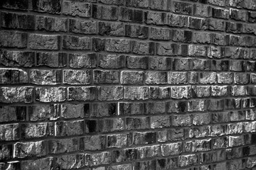 Old weathered bricks of a facade or wall with vanishing point persepective. Black and white background pattern made by masonry craftsmen. Contrasting light and shadow structures in shades of grey.