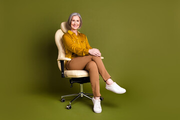 Full length photo of cheerful attractive lady dressed blouse sitting office chair empty space isolated khaki color background