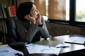 A woman in a business suit is sitting at a desk with a laptop