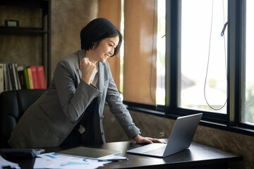 A woman in a business suit is sitting at a desk with a laptop open