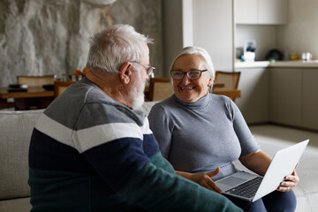 Distraught senior couple e-banking with credit card and laptop at home.	