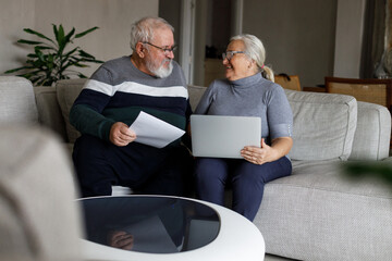 Shot of a mature couple sitting together at home and using a laptop to calculate their finances