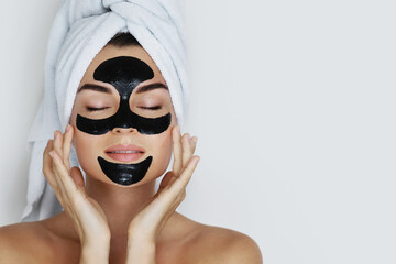 Portrait of a young woman with a charcoal face mask applied to her face