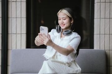 Woman listening to music with headphones and using laptop or smart phone at home Relaxation holiday...