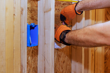 An electrician connects wires to socket box in new building during construction