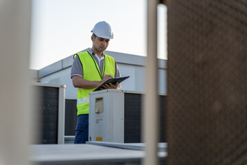Asian maintenance engineer works on the roof of factory. contractor inspect compressor system and...