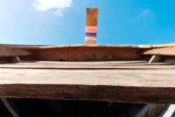The area in front of a long-tailed boat is made of wood and the sky in the background.