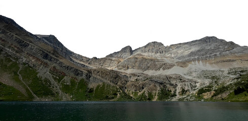 A range of layered rocky mountains across the image with a large green-blue colored lake across the bottom of the frame. The sky is transparent.
