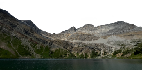 A range of layered rocky mountains across the image with a large green-blue colored lake across the bottom of the frame. The sky is transparent.
