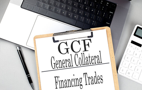 GCF word on clipboard on laptop with calculator and pen