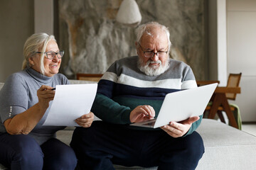 Shot of a mature couple sitting together at home and using a laptop to calculate their finances