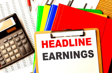 HEADLINE EARNINGS text on clipboard with calculator and color folder