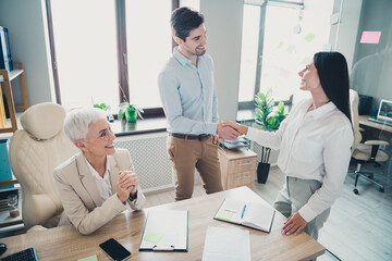 Obraz premium Photo of two employees mature boss woman shake hands office team meeting discussion colleagues working together in workstation
