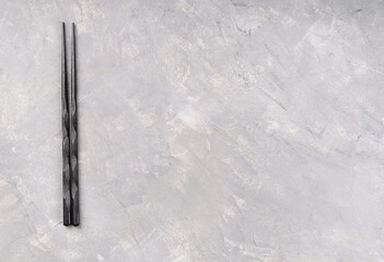 Black Chinese chopsticks on a blank gray background, top view, copy space