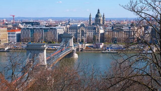 Chained bridge through danube in day light. A view of chained Secheni bridge with public traffic over Danube river against bright cityscape in the day light.
