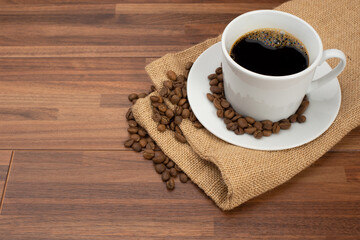 木目テーブルの上に置かれたコーヒーカップとコーヒー豆
