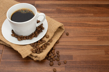 木目テーブルの上に置かれたコーヒーカップとコーヒー豆