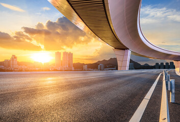 Asphalt highway road and bridge with modern city buildings at sunset