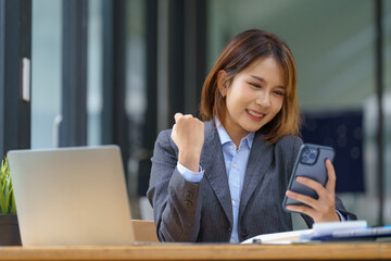 Young pretty Asian businesswomen look at smartphones excited and thrilled with the business success...