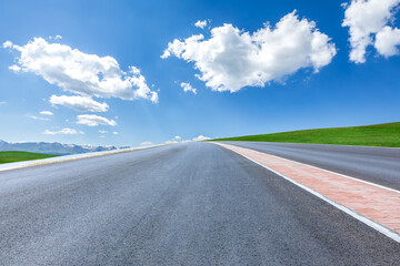 Asphalt highway road and green meadow with mountain nature landscape under blue sky
