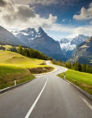 Fototapeta premium transport road in the Alps against the backdrop of snow-capped mountains and forest