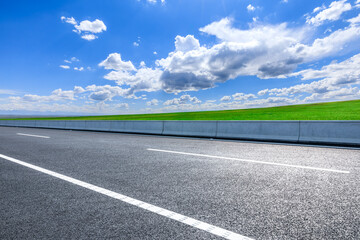 Asphalt highway road and green meadow with mountain nature landscape under blue sky
