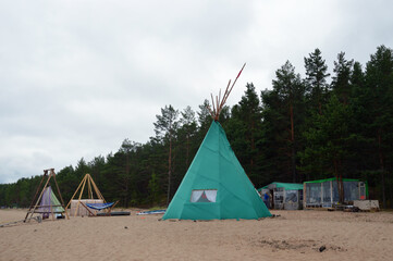 Tourist tepee on sand near forest.