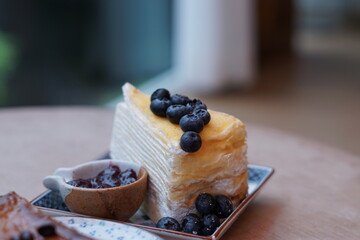 A piece of blueberry crepe cake topped with blueberry on the plate.