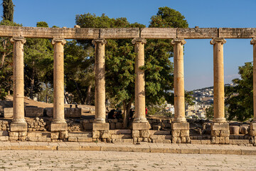 Fototapeta premium Ancient Forum of Gerash, Jordan: Majestic Roman Columns Amidst Scenic Landscape and Historic Ruins