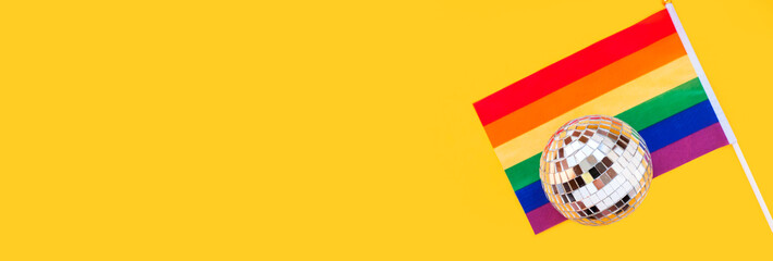 LGBT rainbow flag and disco ball flat lay on yellow color background. gay marriage, human rights,...
