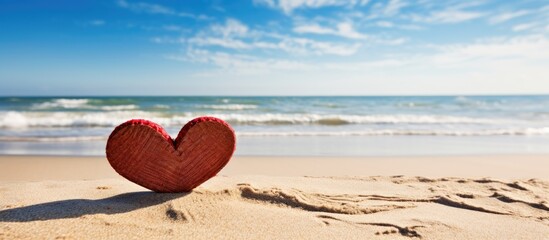 Fototapeta premium A close up of a red wooden cutout in the shape of I love you is placed on the sandy beach representing a honeymoon vacation concept with copy space image 163 characters