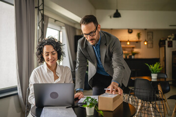 woman and man colleagues check shipment on laptop at cafe