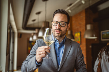 Adult man stand in a winery and hold glass of wine