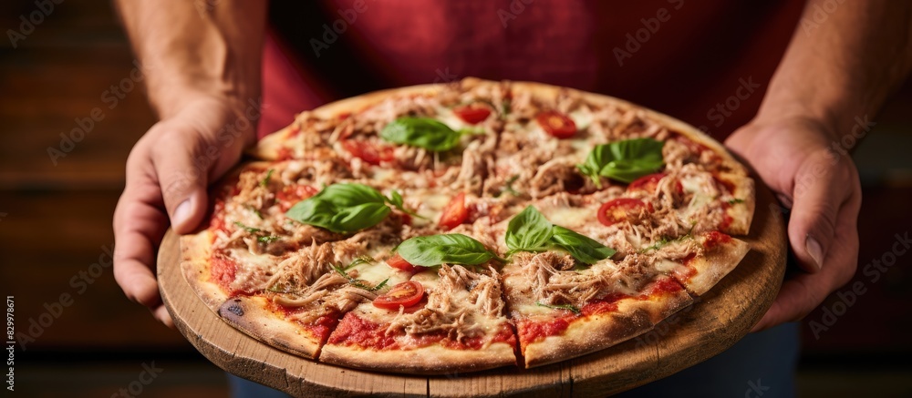 Poster a man holds a homemade tuna pizza with fresh basil while an old wood background creates a rustic set