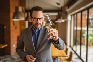 Adult man stand in a winery and hold glass of wine