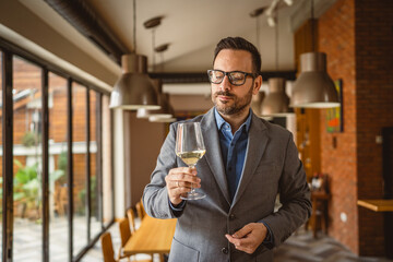 Adult man stand in a winery and hold glass of wine