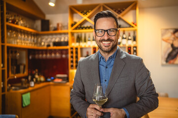 Adult man stand in a winery and hold glass of wine