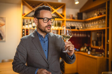 Adult man stand in a winery and hold glass of wine