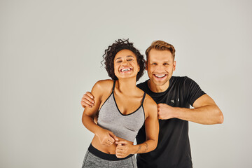 A young interracial sport couple in active wear confidently posing for the camera in a studio...