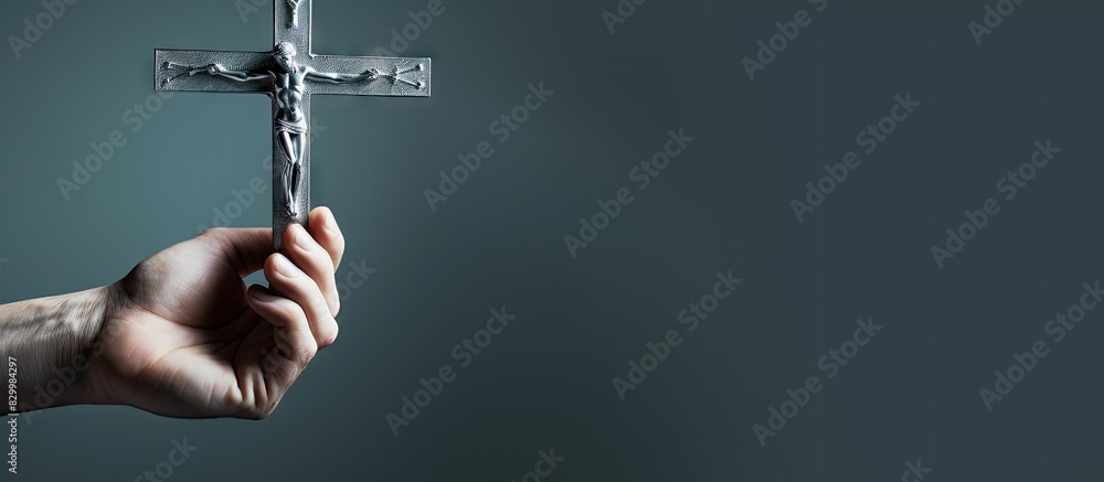 Poster close up image of a hand holding a silver cross with copy space